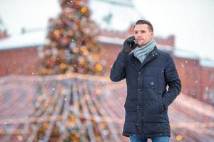 Happy man near fir-tree branch in snow for new year. photo