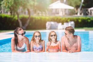 familia feliz de cuatro en la piscina al aire libre foto