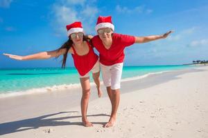 Beautiful couple in Santa hats on tropical beach have fun photo
