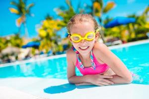 Adorable little girl swimming at outdoor swimming pool photo