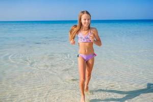 Adorable little girl have fun at tropical beach during vacation photo