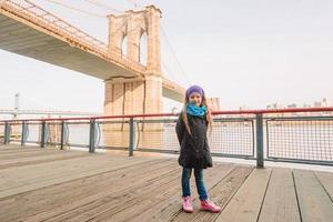 Adorable little girl sitting at Brooklyn Bridge in New York photo