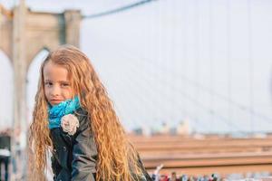 Adorable little girl sitting at Brooklyn Bridge in New York photo