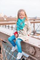 Adorable little girl sitting at Brooklyn Bridge in New York photo