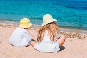 Little happy funny girls have a lot of fun at tropical beach playing together. photo