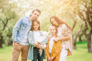 adorable familia en el floreciente jardín de cerezos en un hermoso día de primavera foto