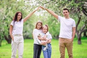 adorable familia en el floreciente jardín de cerezos en un hermoso día de primavera foto