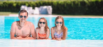 Happy family of three in outdoors swimming pool photo