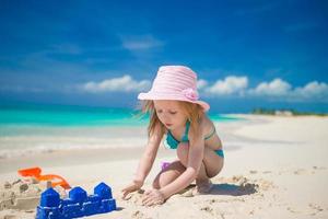 Little cute girl playing with beach toys during tropical vacation photo