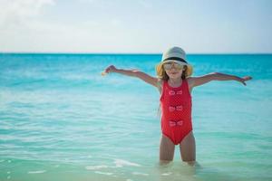 Adorable little girl in hat on beach during summer vacation photo