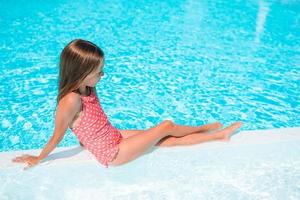 Adorable little girl swimming at outdoor swimming pool photo