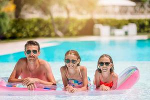 Happy family of three in outdoors swimming pool photo