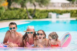 Happy family of four in outdoors swimming pool photo