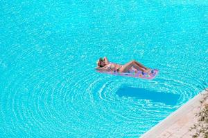 mujer hermosa joven que disfruta de las vacaciones de verano en la piscina de lujo foto