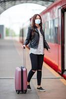 joven turista con equipaje en el andén esperando el tren foto