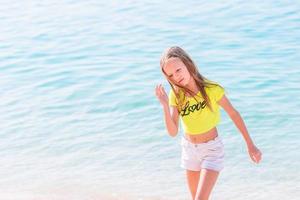 Adorable little girl have fun at tropical beach during vacation photo