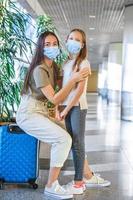 madre y niña con máscaras médicas en el aeropuerto. protección contra coronavirus y grip foto