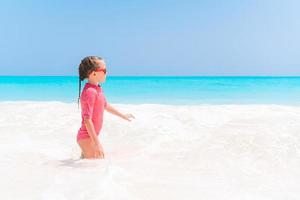 una niña adorable se divierte en la playa tropical durante las vacaciones foto