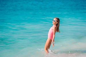 Adorable little girl have fun at tropical beach during vacation photo