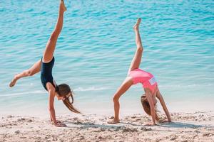 Little happy funny girls have a lot of fun at tropical beach playing together. photo