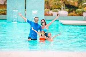 Happy family of four in outdoors swimming pool photo