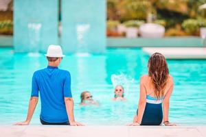 Happy family of four in outdoors swimming pool photo