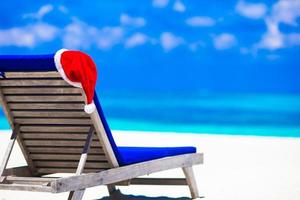 Salón de tumbonas con sombrero rojo de Papá Noel en una playa blanca tropical y aguas turquesas foto