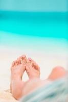 Woman's feet on the white sand beach in shallow water photo