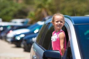 Little adorable girl in the car looking throw window at summer vacation photo