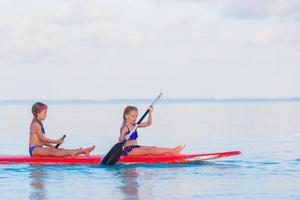 niñas lindas nadando en tablas de surf durante las vacaciones de verano foto