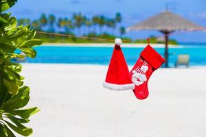 Red Santa hat and Christmas stocking on the beach photo