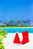 Red Santa hat and Christmas stocking between palm trees photo