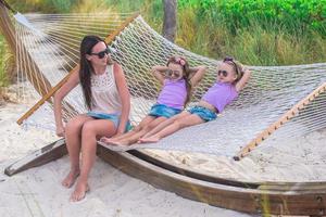 Mother and little daughters relaxing in hammock on summer vacation photo