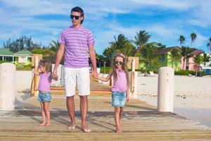 padre e hijos caminando en un muelle de madera durante las vacaciones en la playa foto