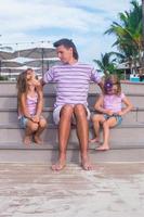 familia de tres sentados en la playa disfrutando de la vista al mar foto