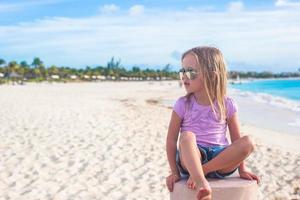 Adorable little girl sitting in a lotus position on an exotic beach photo