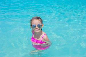 Adorable little girl in the sea on tropical beach vacation photo