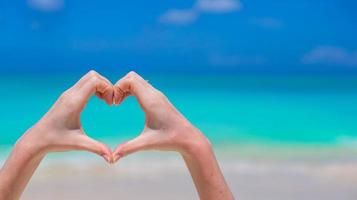 Closeup of heart made by hands background turquoise water photo