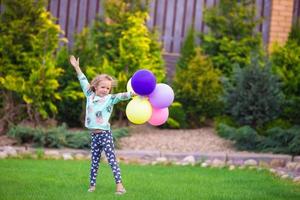 Happy little girl playing with balloons outdoors photo