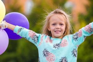 Portrait of happy little girl playing with balloons outdoors photo