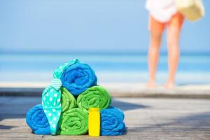 concepto de accesorios de playa y verano: toallas coloridas, traje de baño y fondo solar hermosa mujer foto