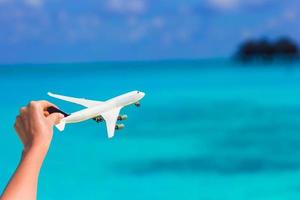 pequeña miniatura blanca de un avión sobre el fondo del mar turquesa foto