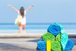 concepto de accesorios de playa y verano: toallas coloridas, traje de baño y fondo solar hermosa mujer foto