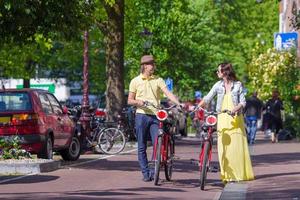 Young happy caucasian couple on bikes in old streets in Amsterdam photo