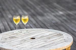 Two glasses of tasty white wine at sunset on wooden table photo