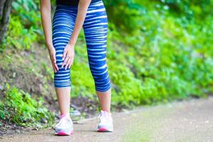 atleta femenina que sufre de dolor en la pierna mientras hace ejercicio al aire libre foto