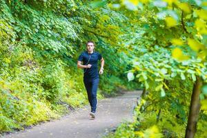Sporty fit young man jogging while listening music on smarthphone outdoor photo