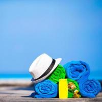 Beach and summer vacation accessories concept - close-up of colorful towels, hat, swimming goggles and sunblock photo
