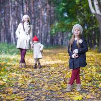 las niñas lindas y la madre joven en el parque de otoño se divierten foto