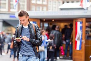 Happy caucasian tourist with fresh herring with onion and netherland flag in Amsterdam. Traditional dutch food outdoor photo